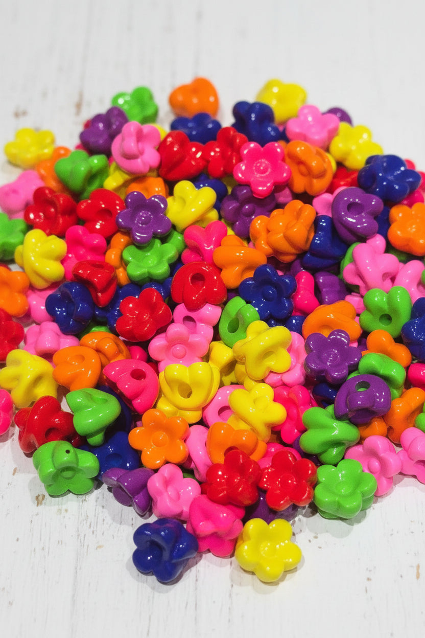 A dense pile of small, glossy, flower-shaped acrylic beads in a vibrant rainbow of colors including pink, red, orange, yellow, green, blue, and purple.