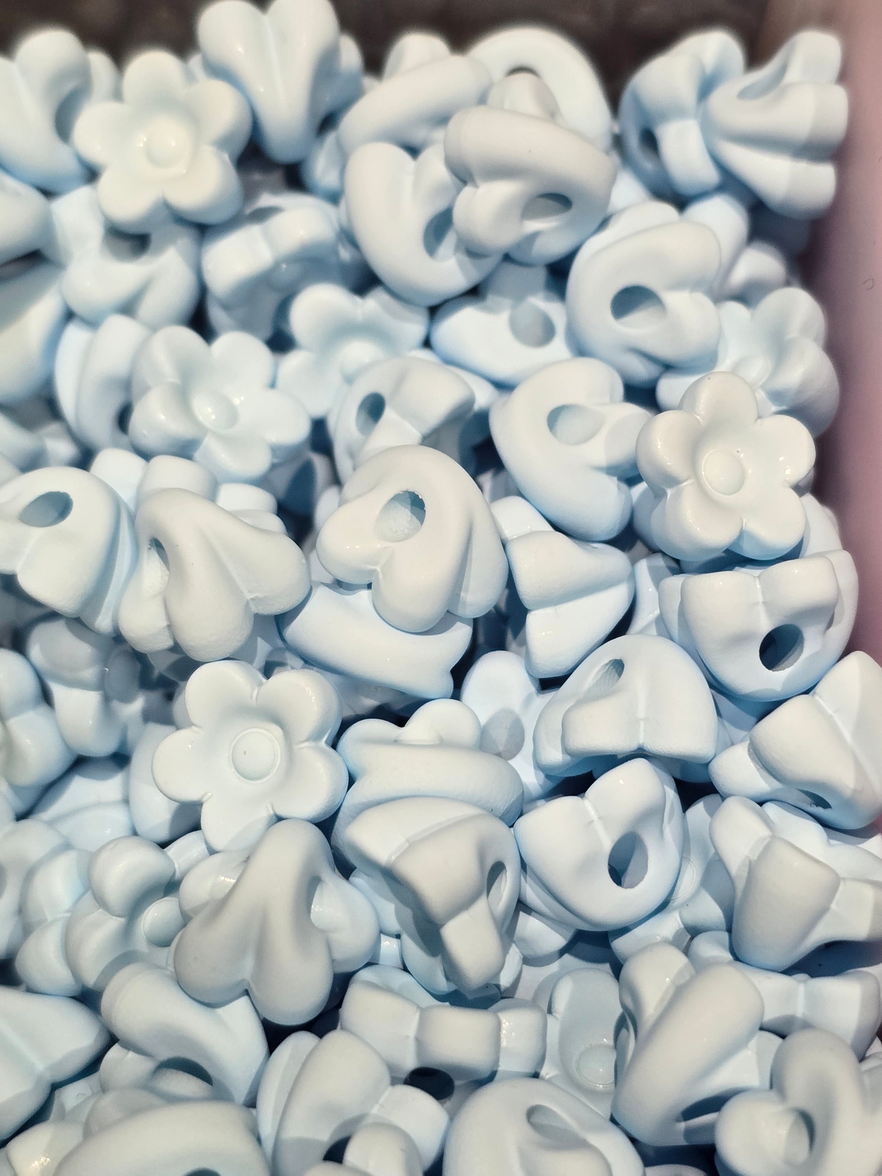 A close-up pile of small white flower-shaped beads will also fit pens
