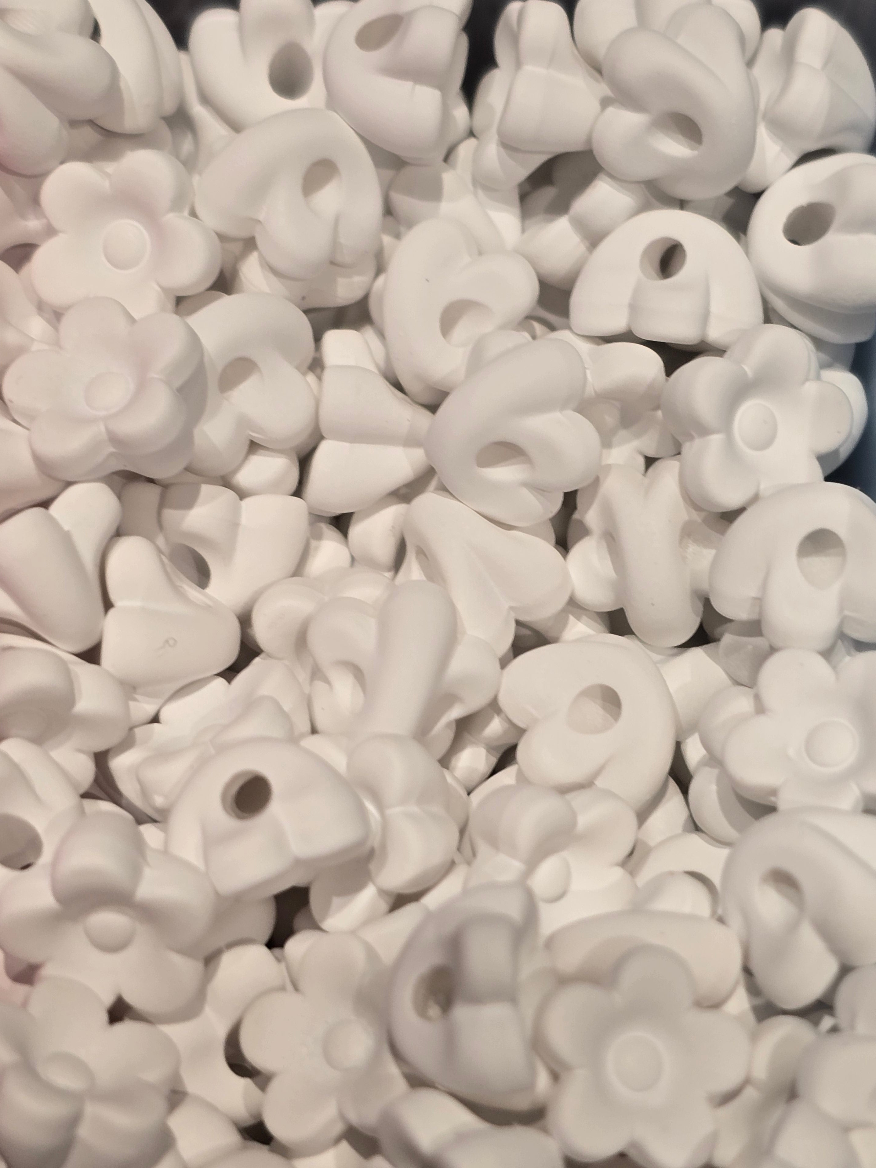 A close-up pile of small white flower-shaped beads will also fit pens