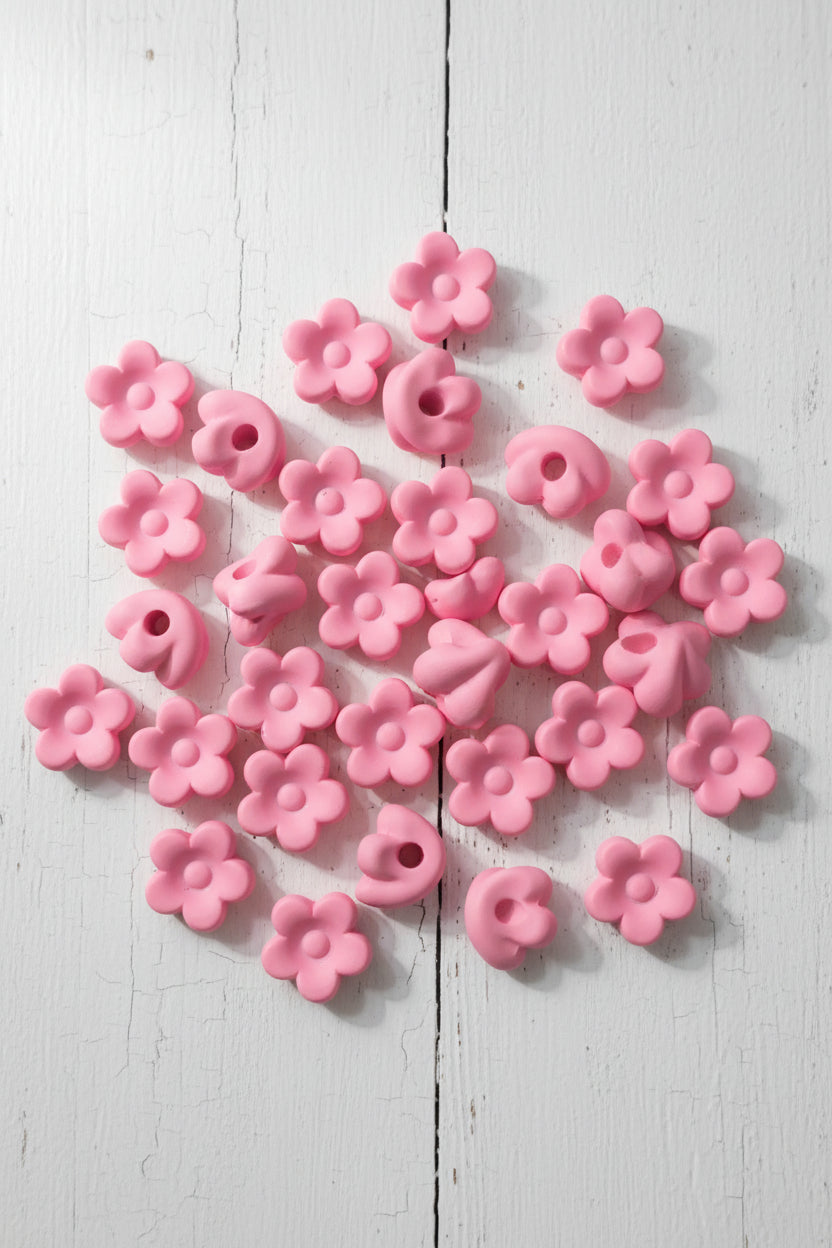 A close-up pile of small white flower-shaped beads will also fit pens