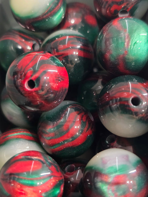 A close-up pile of round glass beads with a marbled swirl pattern of red, green, black, and white.