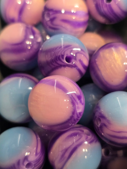 Close-up of glossy round beads with a marbled swirl pattern in purple, light blue, and pale pink.