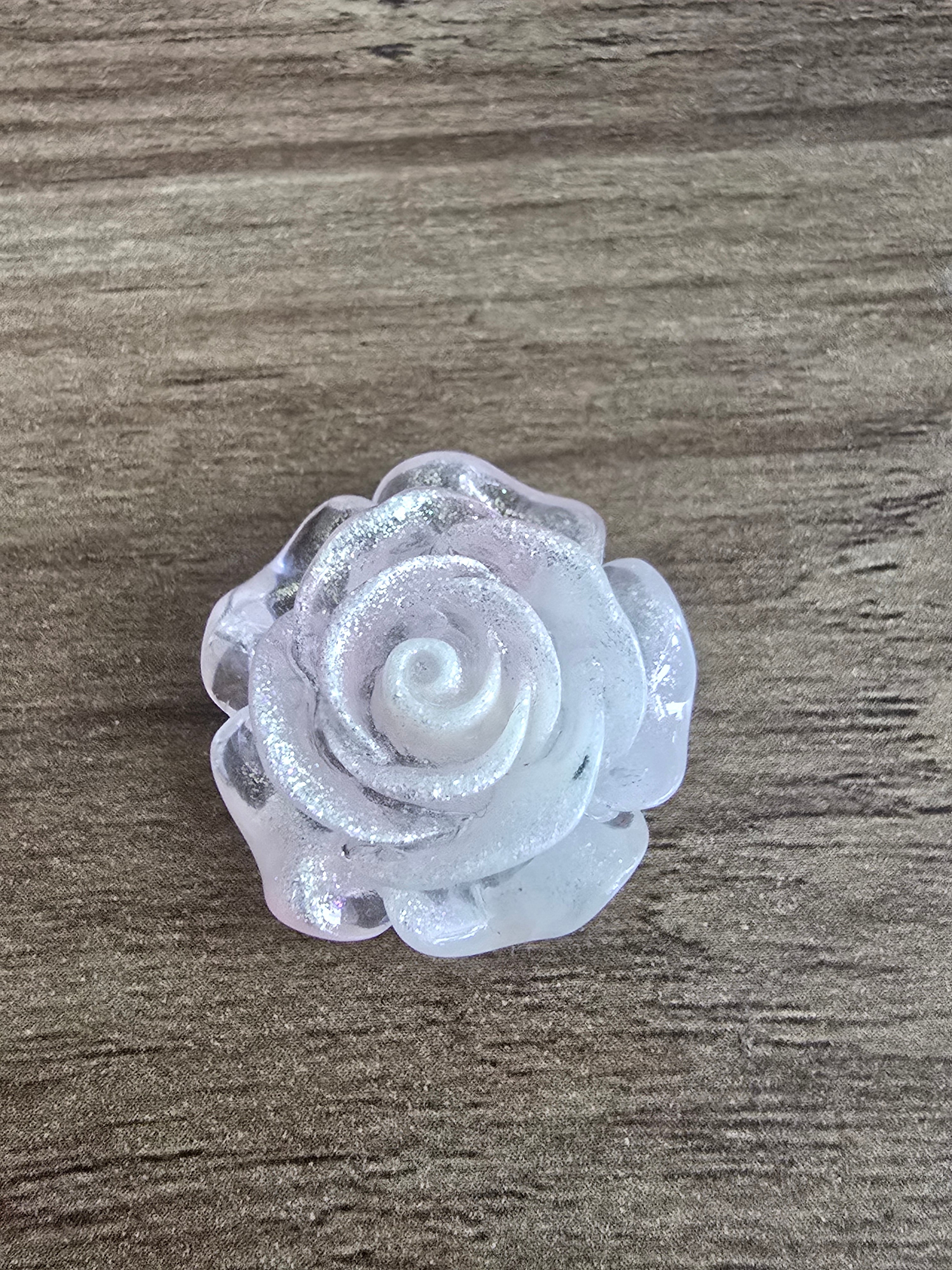 A single pink glittery rose-shaped bead, photographed from above.