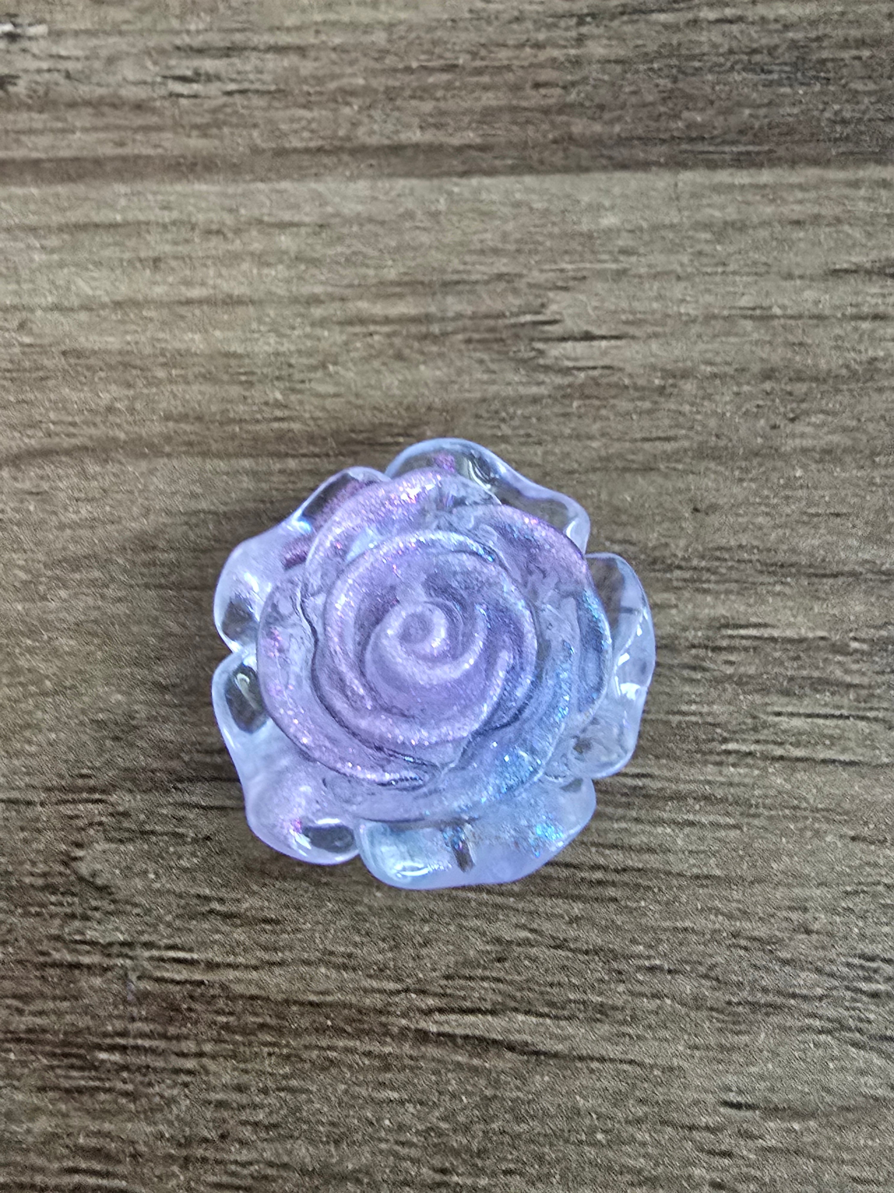 A single blue glittery rose-shaped bead, photographed from above.