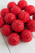 A close-up of multiple round red rhinestone-covered beads 