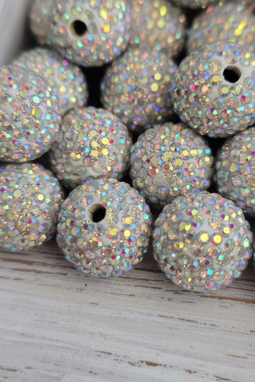 A close-up of multiple round white beads covered in iridescent rhinestones.