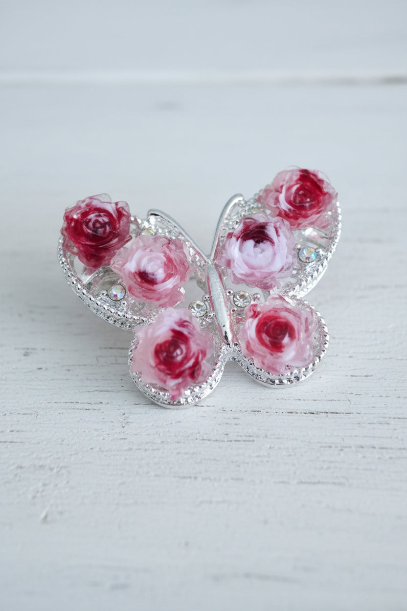 A butterfly-shaped bead featuring pink and red 3D roses 