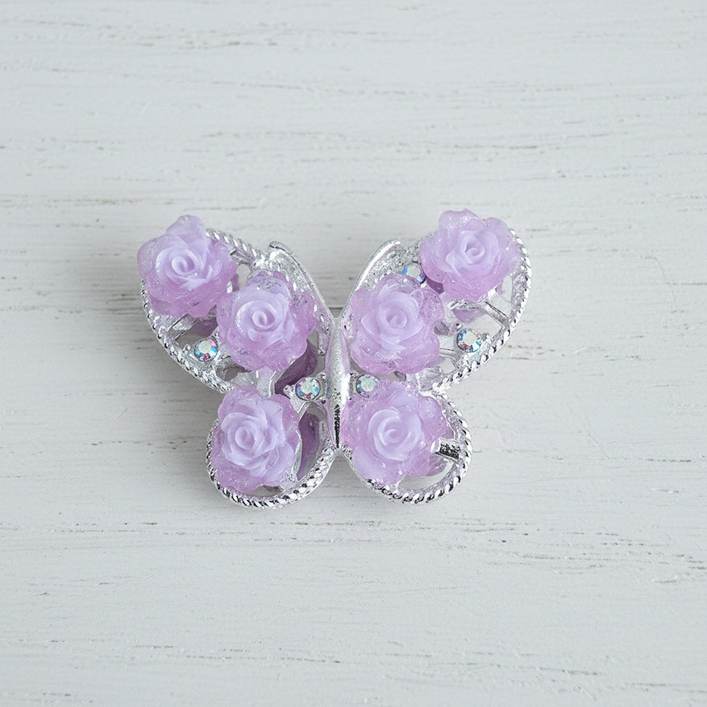 A butterfly-shaped bead featuring light pink roses in a silver-toned filigree frame.