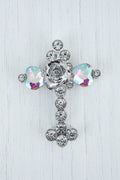 A silver-toned metal cross-shaped bead embellished with clear rhinestones and two faceted iridescent glass crystals showing purple, blue, and green reflections and a silver rose in the centre.