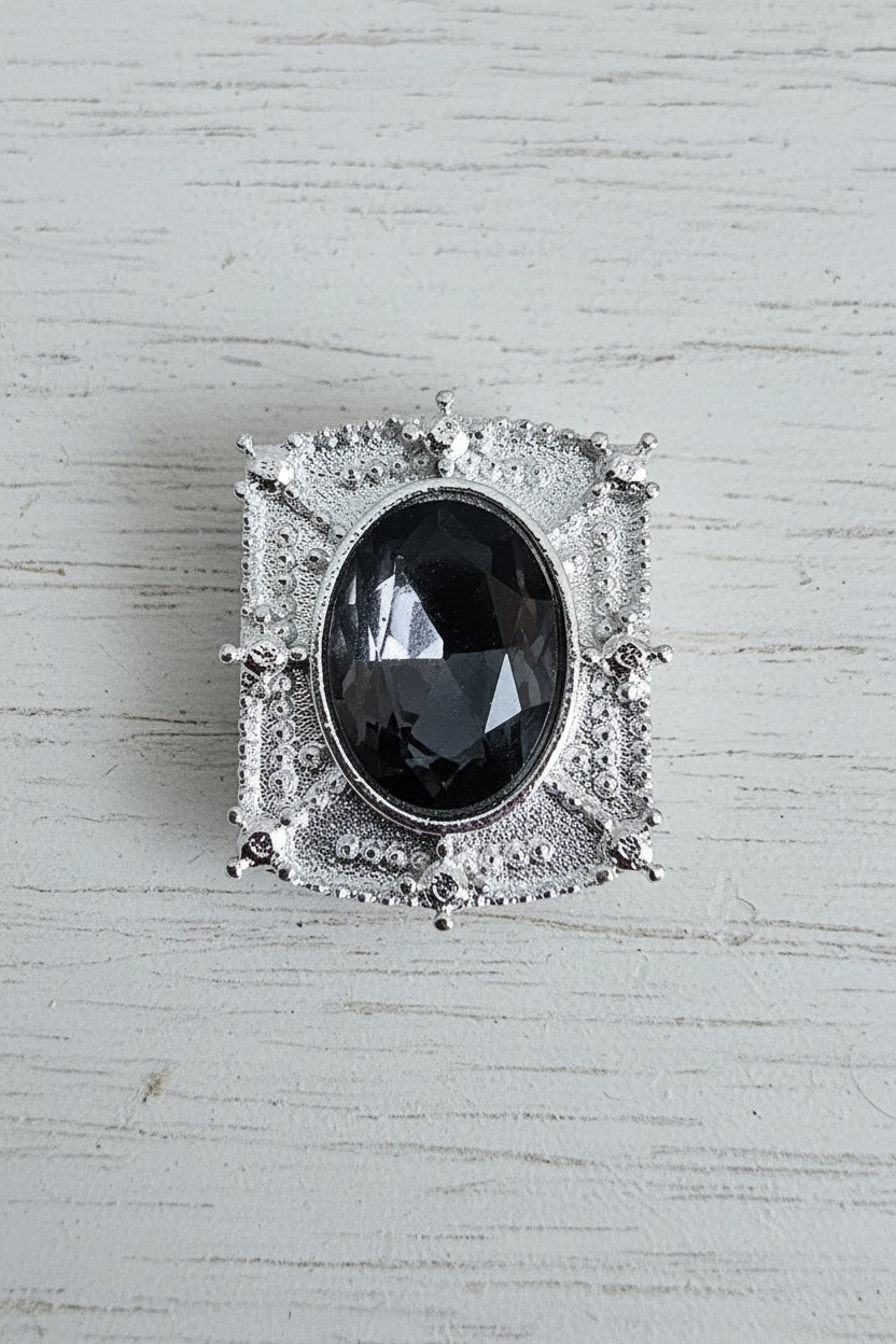 A silver-toned square bead featuring a large oval dark gray gemstone in the center.