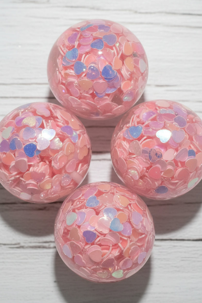 Pink resin beads filled with small iridescent heart-shaped confetti.