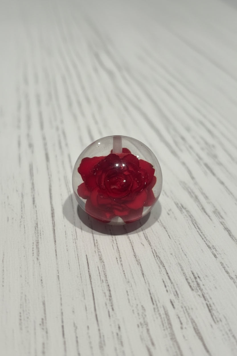 A resin bead containing a red rose.