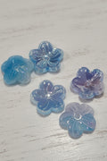 Translucent flower-shaped resin charms in shades of light blue, lavender, and aqua.