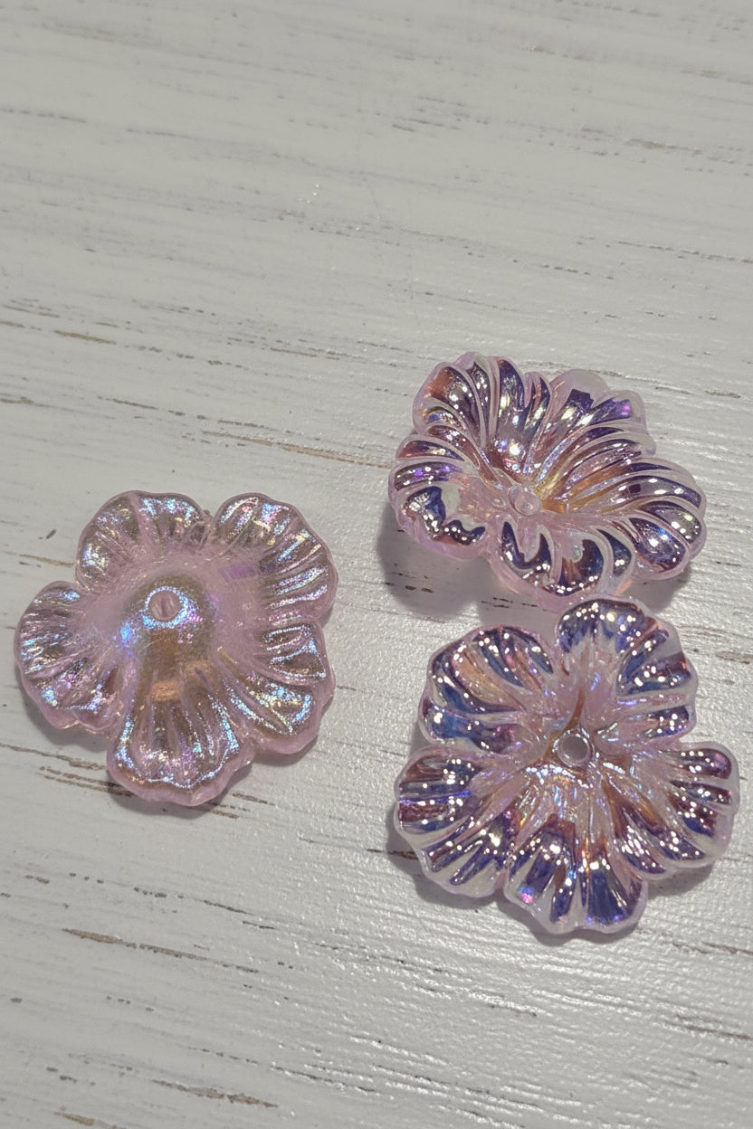 Three iridescent pink flower-shaped beads.