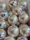 A close-up of round iridescent pearl-like beads with a, showing a pearlescent white base with shifting pastel rainbow reflections.