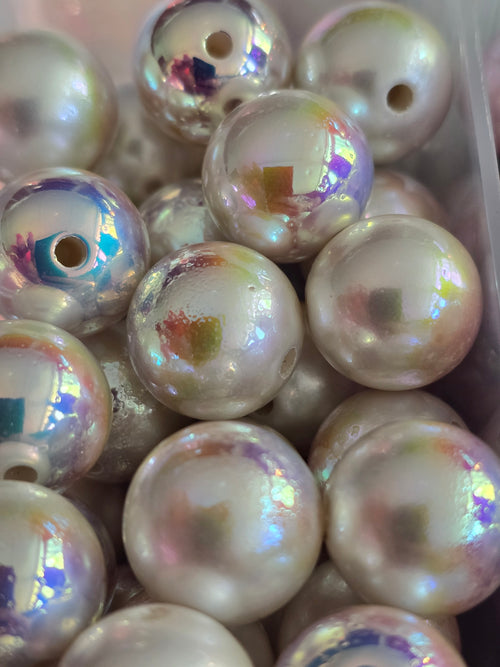A close-up of round iridescent pearl-like beads with a, showing a pearlescent white base with shifting pastel rainbow reflections.