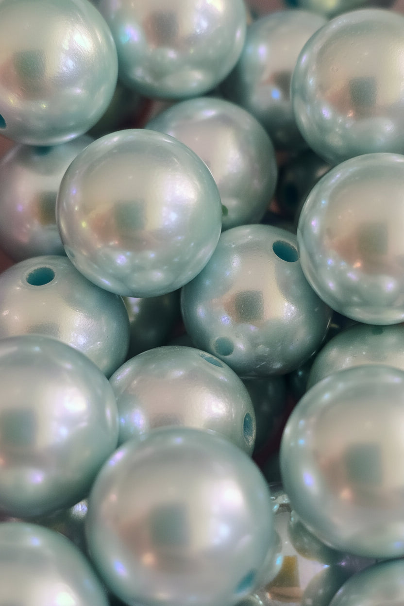 A close-up pile of round iridescent beads with a pearlescent finish and a single hole, reflecting light and showing a colorful mirror-like surface.