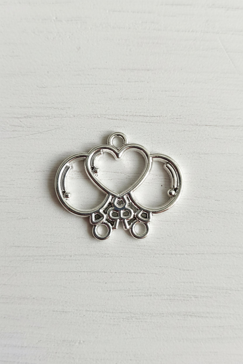 A silver metal jewelry finding, specifically a heart-shaped connector charm with loops and decorative cutouts.