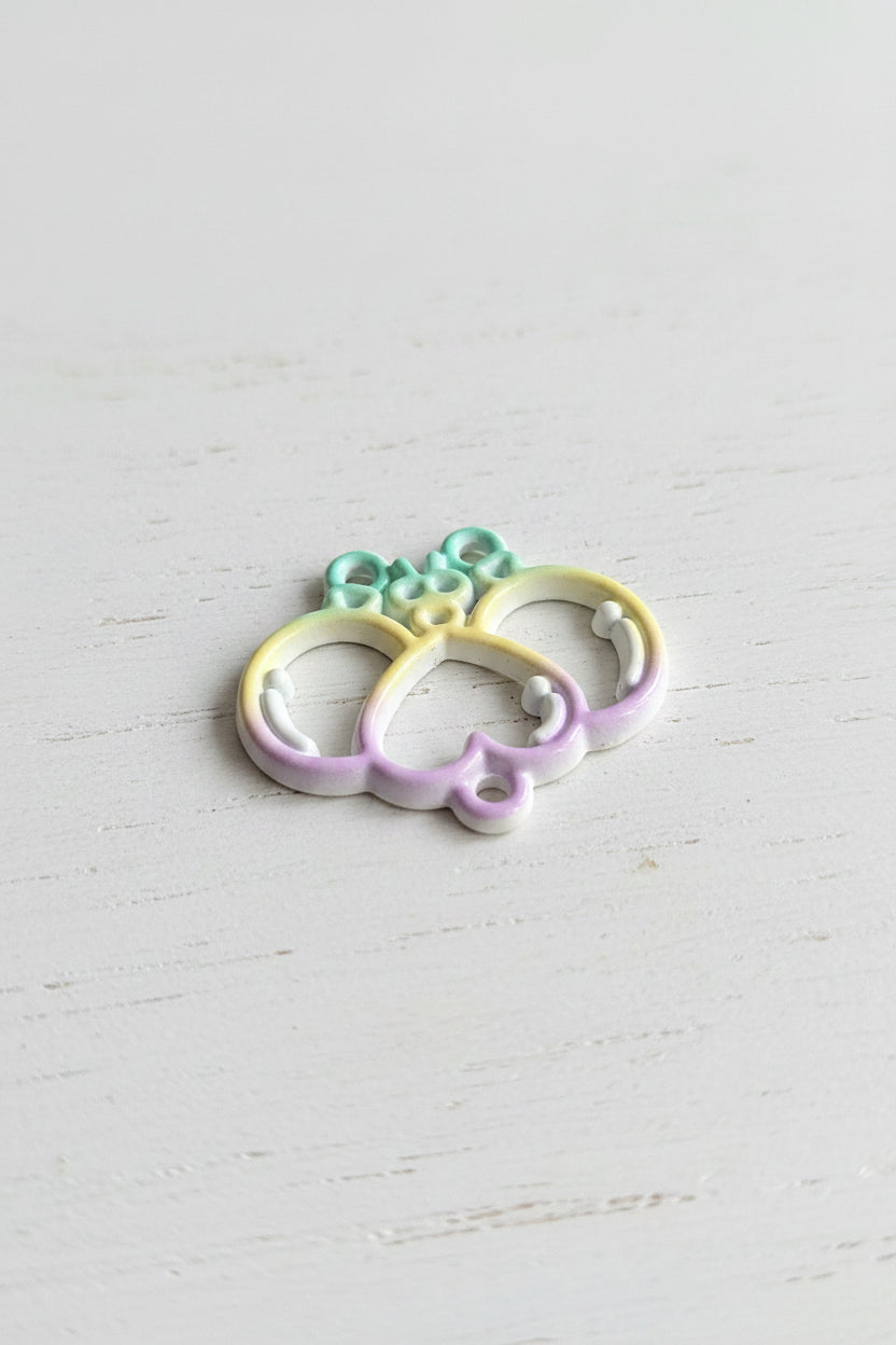 A small iridescent pastel butterfly-shaped jewelry finding or charm with three loops on the left.