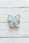 A butterfly-shaped clear resin bead filled with silver glitter.