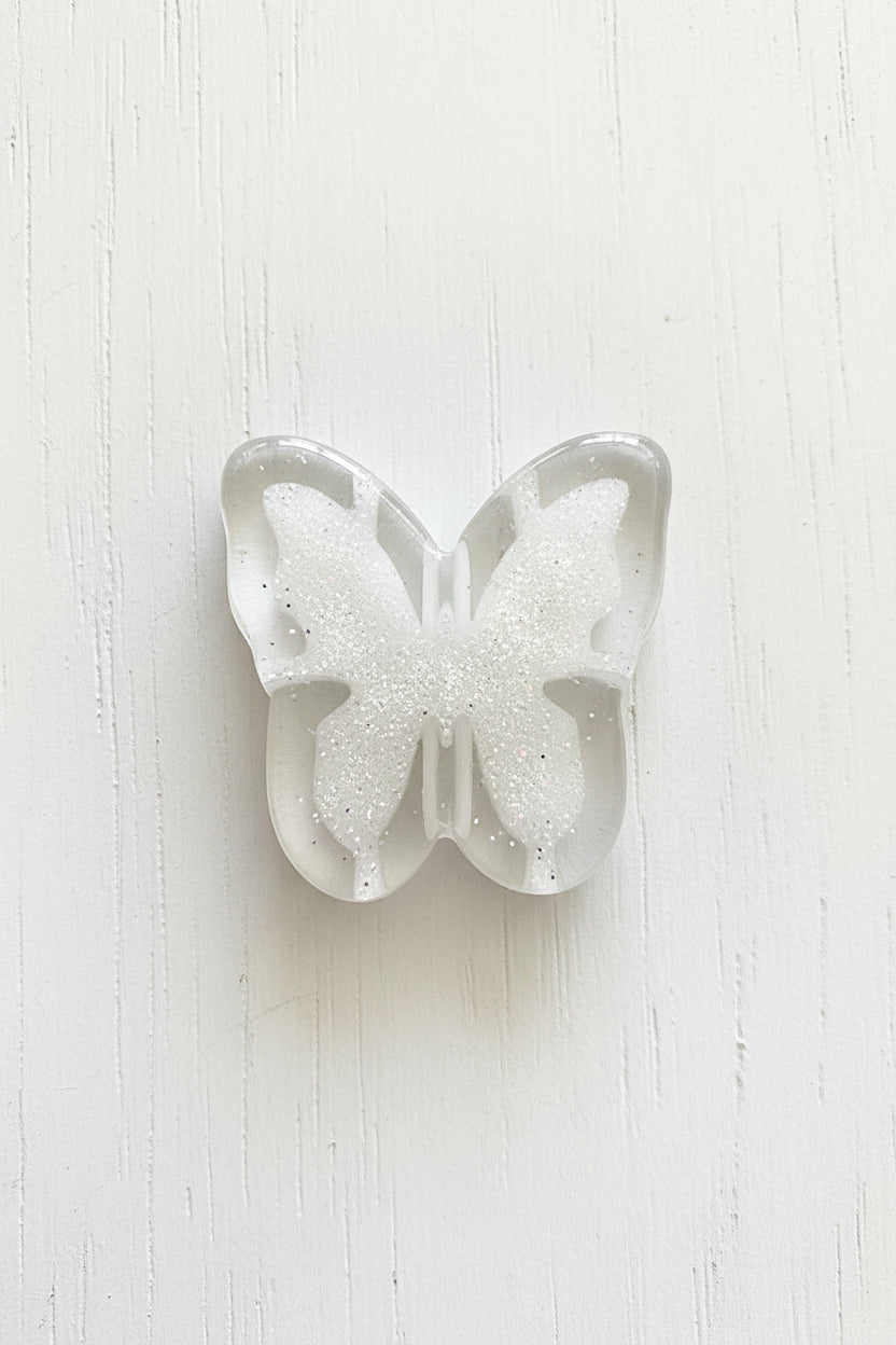 A butterfly-shaped clear resin bead.