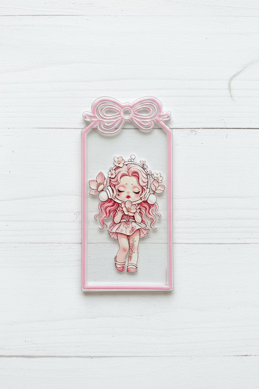 A rectangular acrylic tag featuring a pink and white illustrated girl with long wavy hair, surrounded by flowers, with a pink bow-shaped cutout.