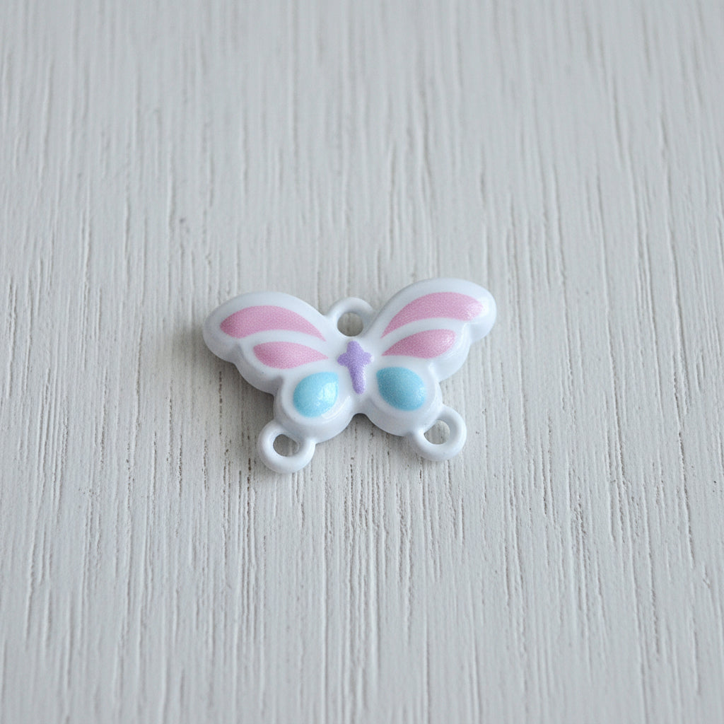 A small metal butterfly-shaped connector with pink and light blue accents on a white base.