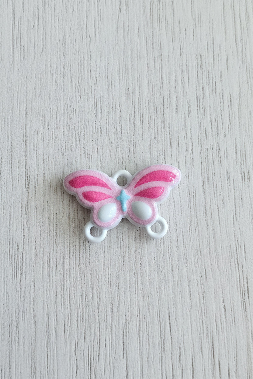 A small metal butterfly-shaped connector with pink and white wings and a light blue center.