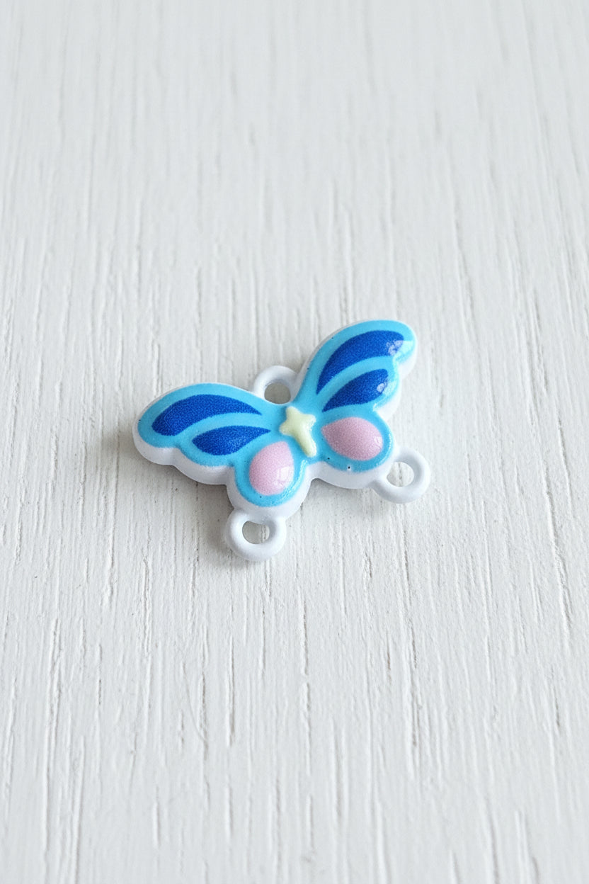 A small metal butterfly-shaped connector with blue and white wings, pink accents, and a small yellow star detail.