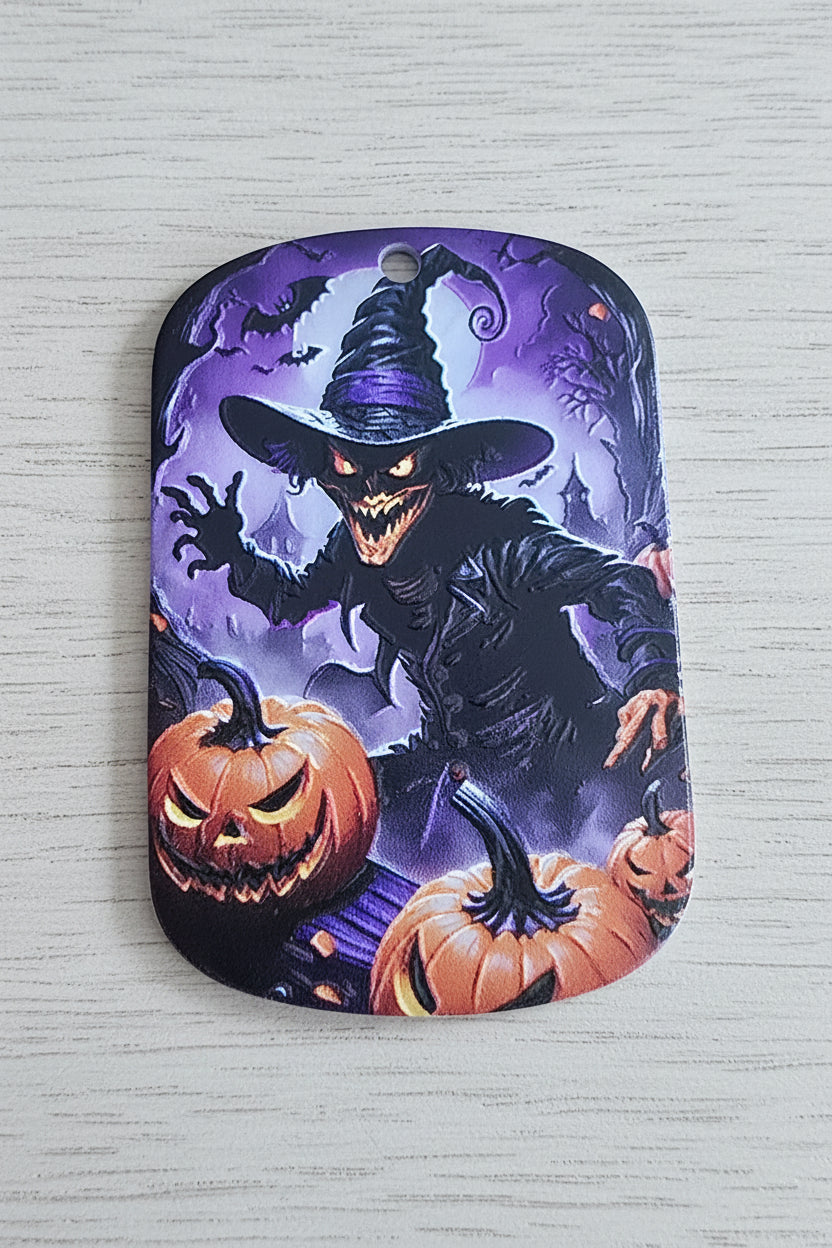A rectangular acrylic tag with rounded corners featuring a Halloween design of a witch flying on a broomstick between jack-o'-lantern pumpkins against a purple sky.