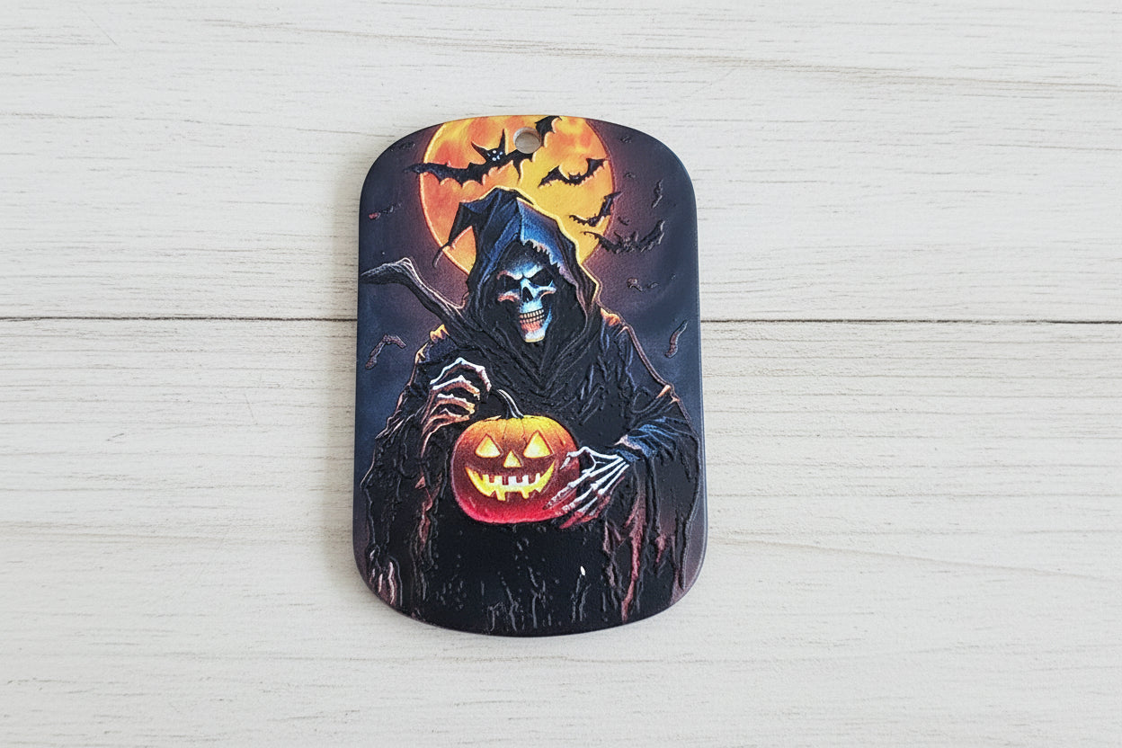 A rectangular Halloween-themed tag with rounded corners, featuring a grim reaper holding a glowing jack-o'-lantern next to a full moon and bats.