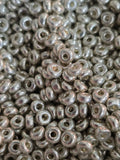 A close-up pile of small metallic silver glass seed beads with a glossy finish.