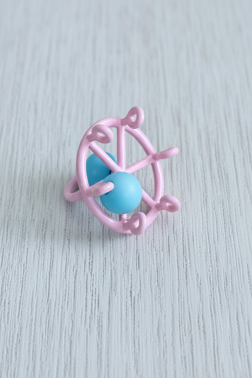 A small pink decorative wheel accessory with a white bow detail. Underside view
