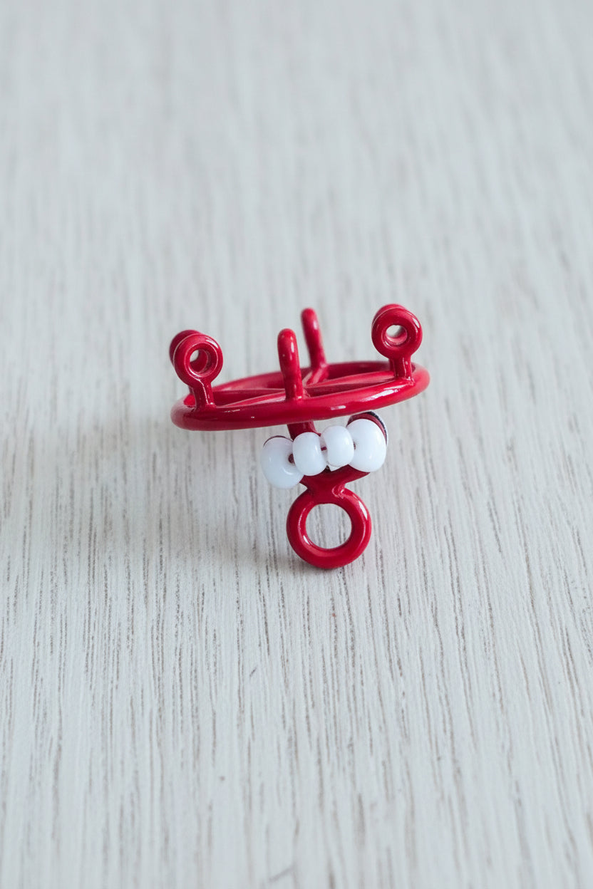A small red decorative wheel charm with a white bow in the center
