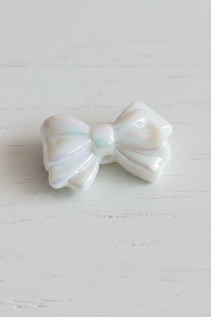 An iridescent white bow-shaped bead.