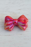 A glossy, iridescent red bow bead.