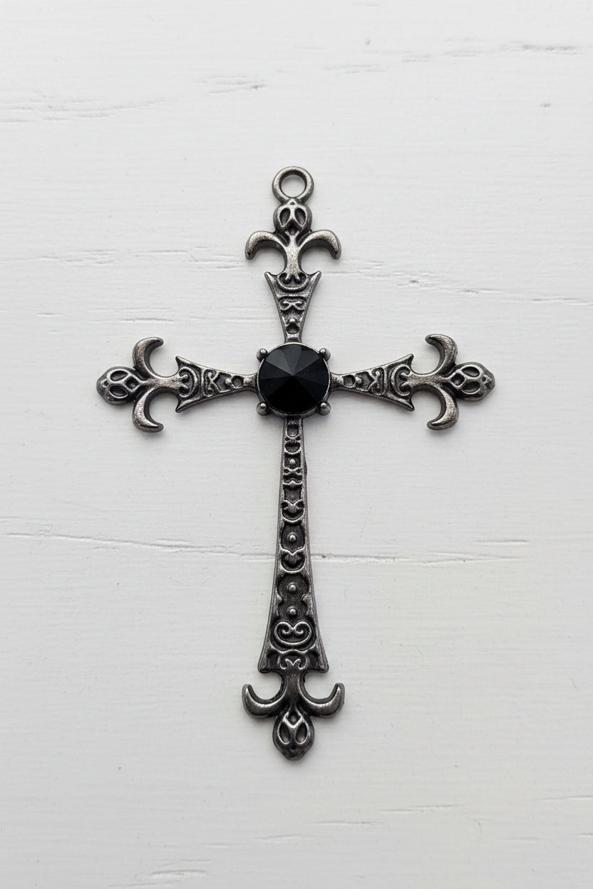 An ornate silver-toned metal cross pendant with a central black oval stone.