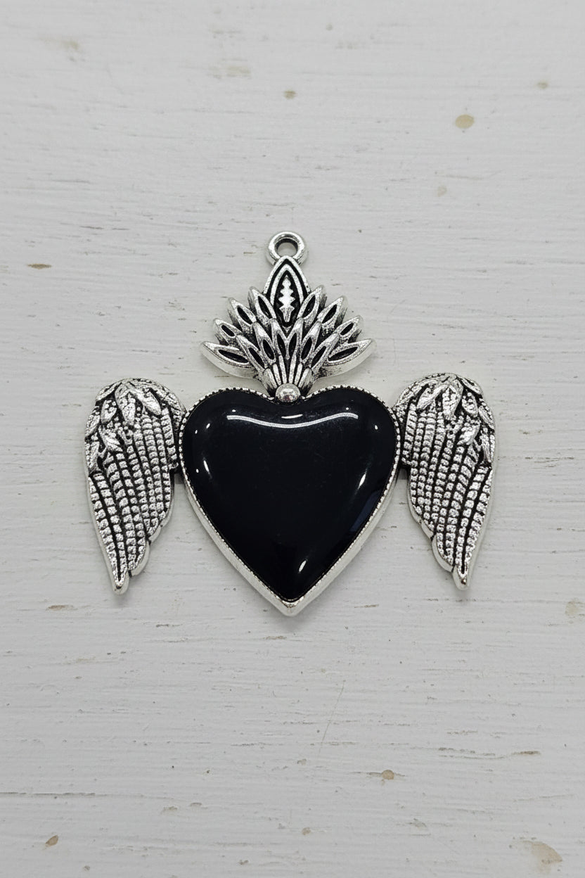 A heart-shaped black pendant with silver angel wings and a silver flame-like top detail.