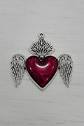 A silver-toned pendant charm featuring a central red heart with silver wings.