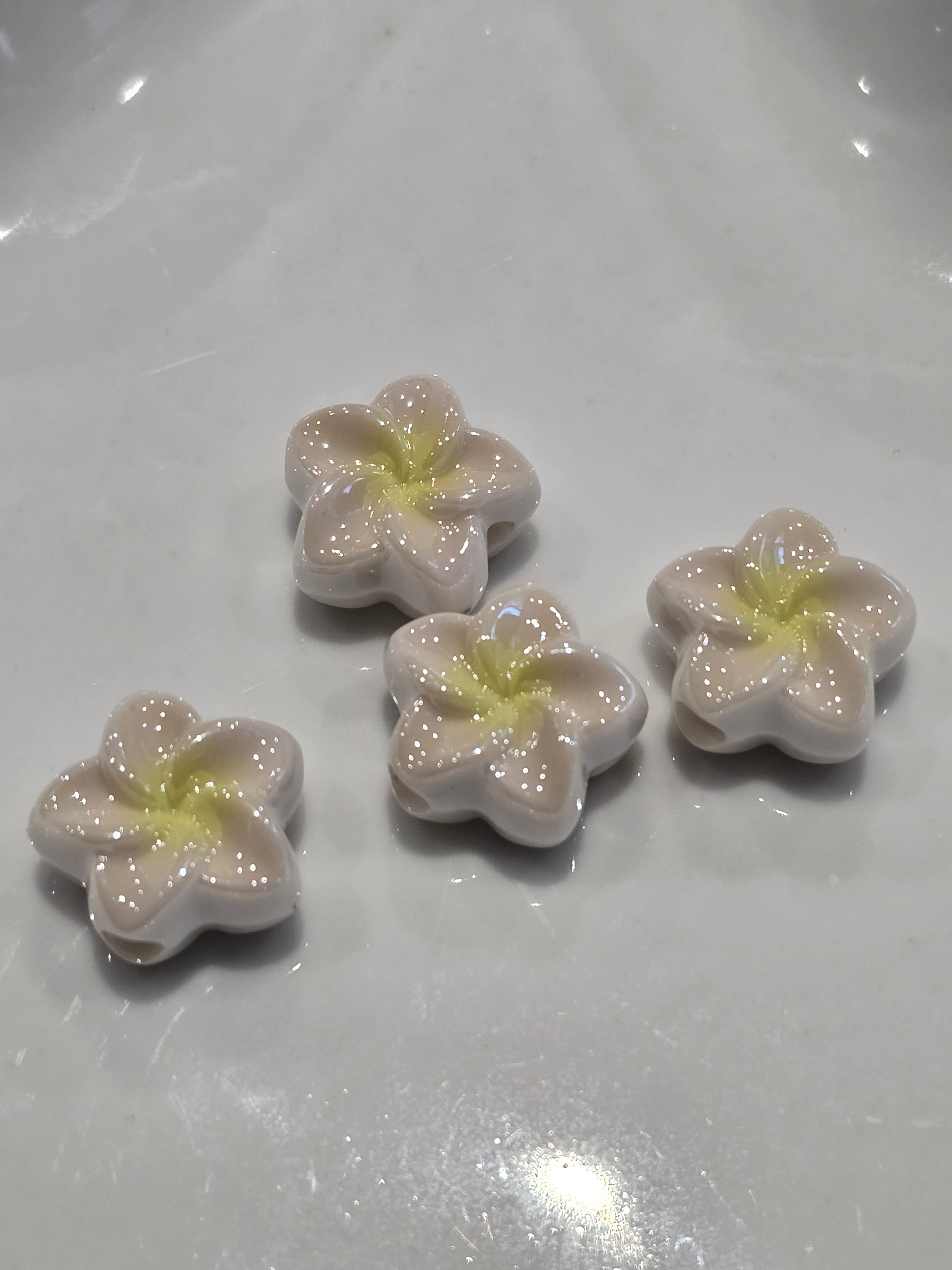 Acrylic flower-shaped beads with glossy off-white petals and pale yellow centres.