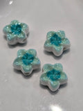 Acrylic flower-shaped beads with white petals and a sparkling light blue centre.