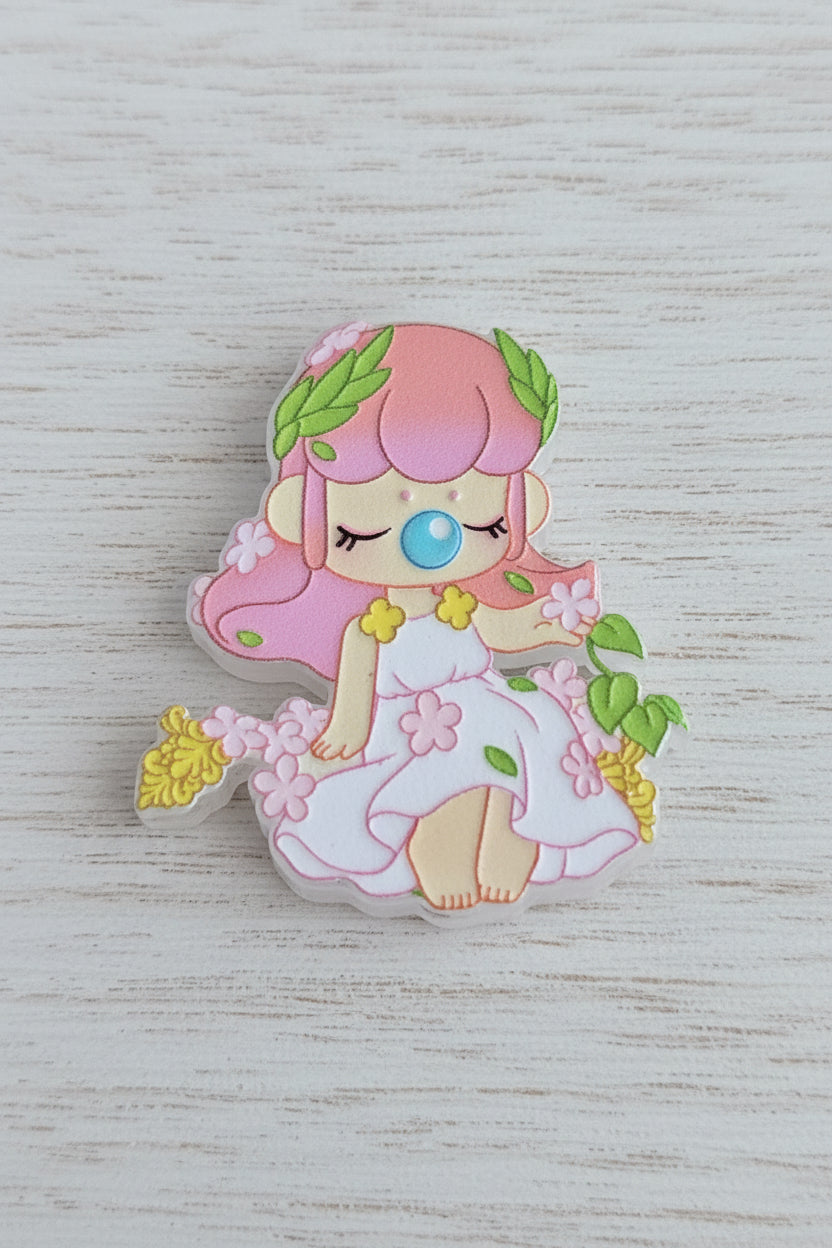 Acrylic focal bead of a cute fantasy girl with pink hair, green leaves, and a white dress decorated with flowers.