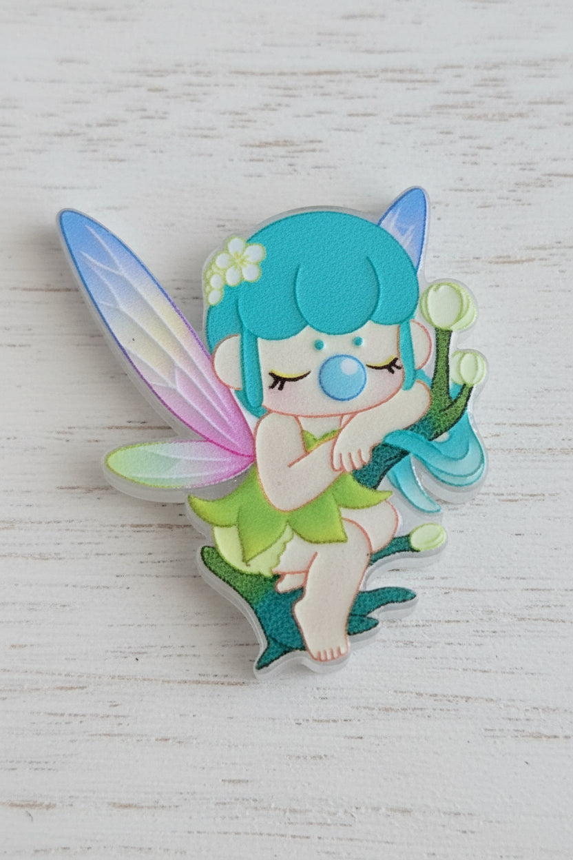 A colorful fairy-shaped acrylic bead with turquoise hair, pastel wings, and a green dress.