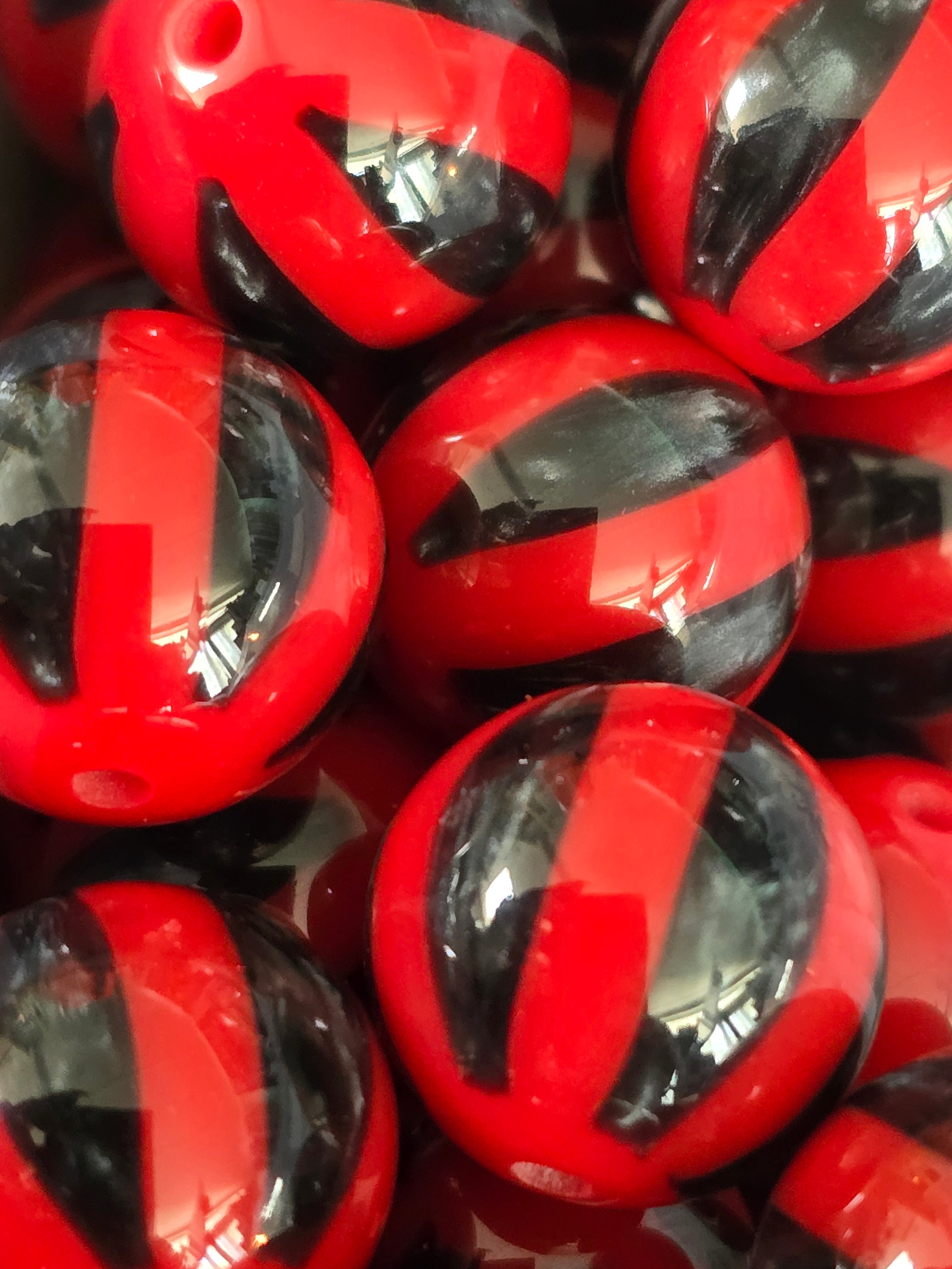 A close-up pile of glossy red and black striped round 16mm beads.