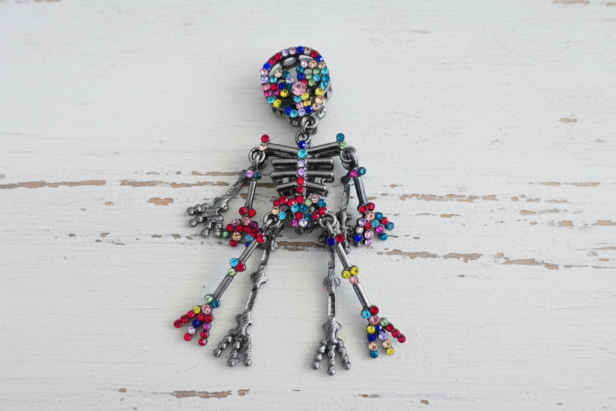 A skeleton-shaped bead made of silver-toned metal and covered with colorful rhinestones.