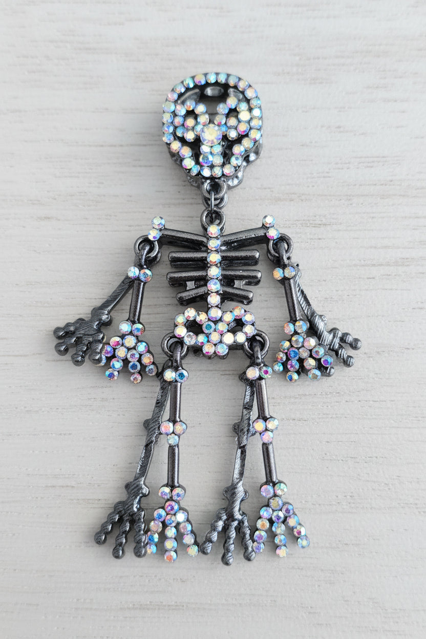 A skeleton-shaped dangling bead made of dark silver-toned metal and covered with iridescent rhinestones.