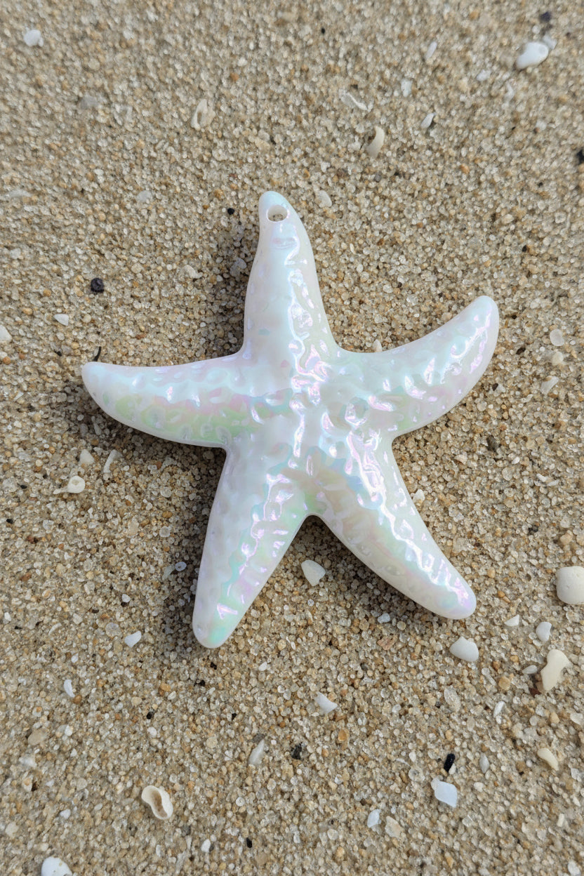 A starfish-shaped acrylic pendant with an iridescent, opalescent finish showing pink, green, and white hues.