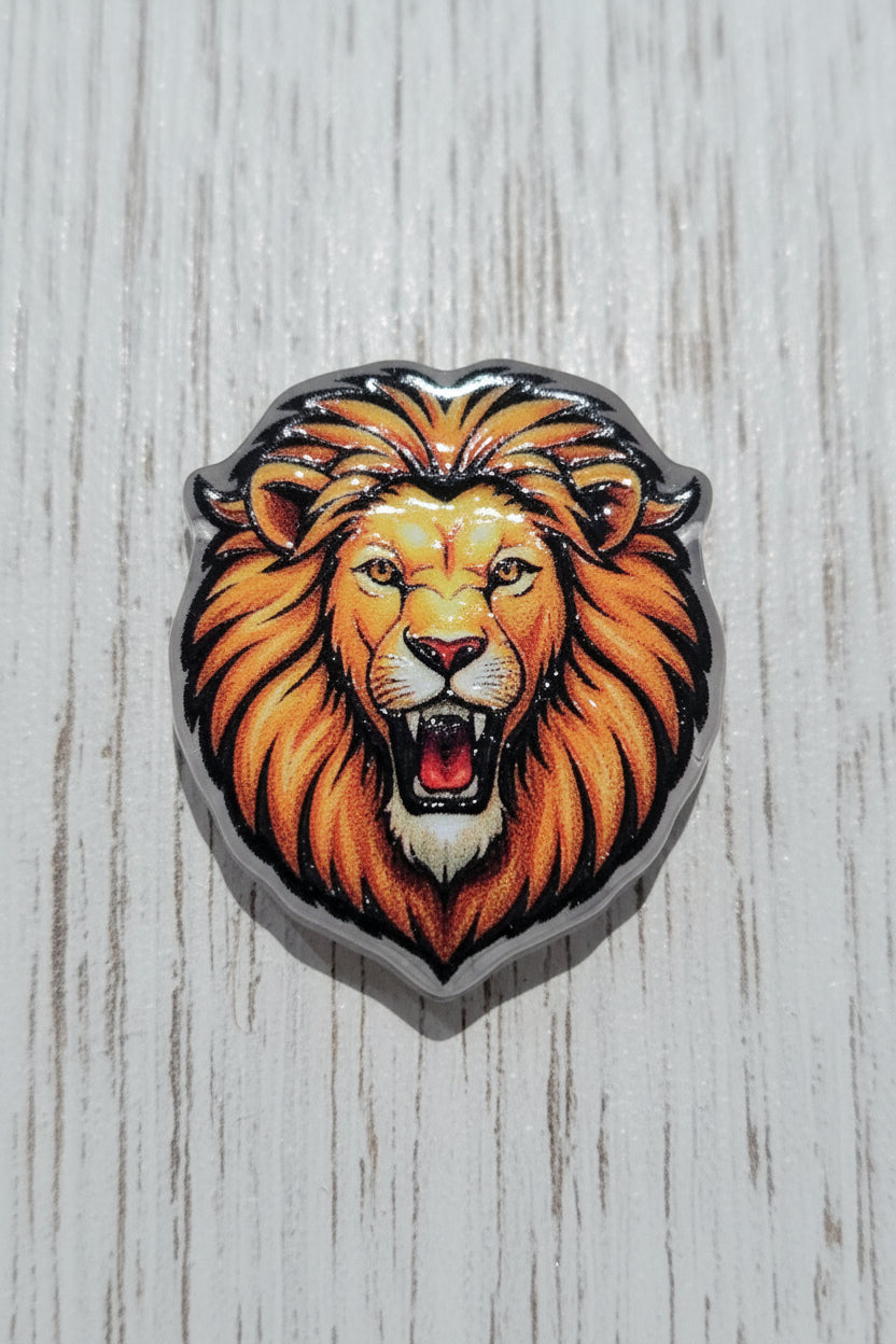 An acrylic bead depicting a roaring lion's head with a vibrant orange and yellow mane, black outlines.