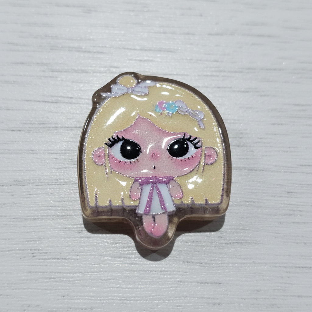 A small decorative bead featuring a cartoon doll face with large black eyes, pink cheeks and lips, blonde hair, and a pink-and-white dress.