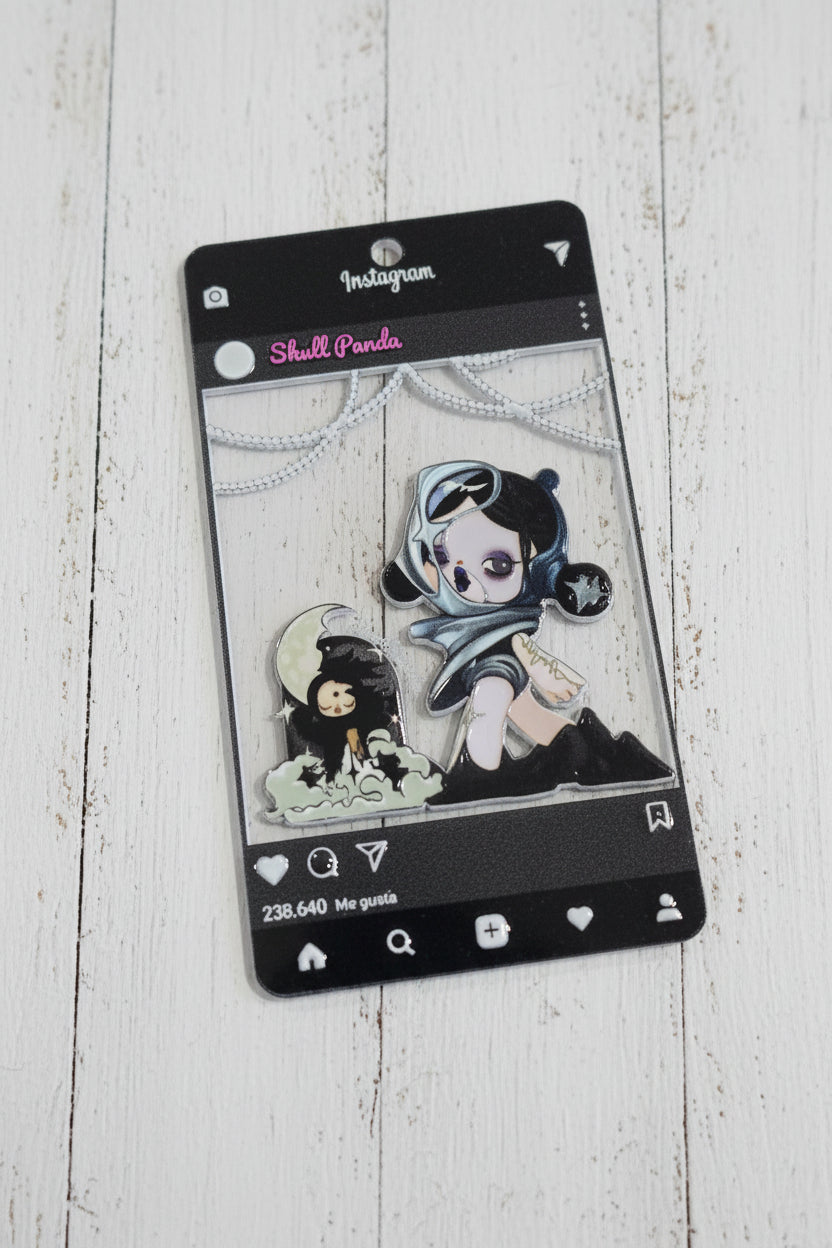 An acrylic tag featuring a stylized anime character with a skull motif and a crescent moon, displayed on its black Instagram-style card.